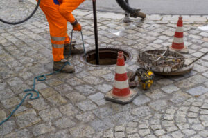 sewerage worker on street cleaning pipe